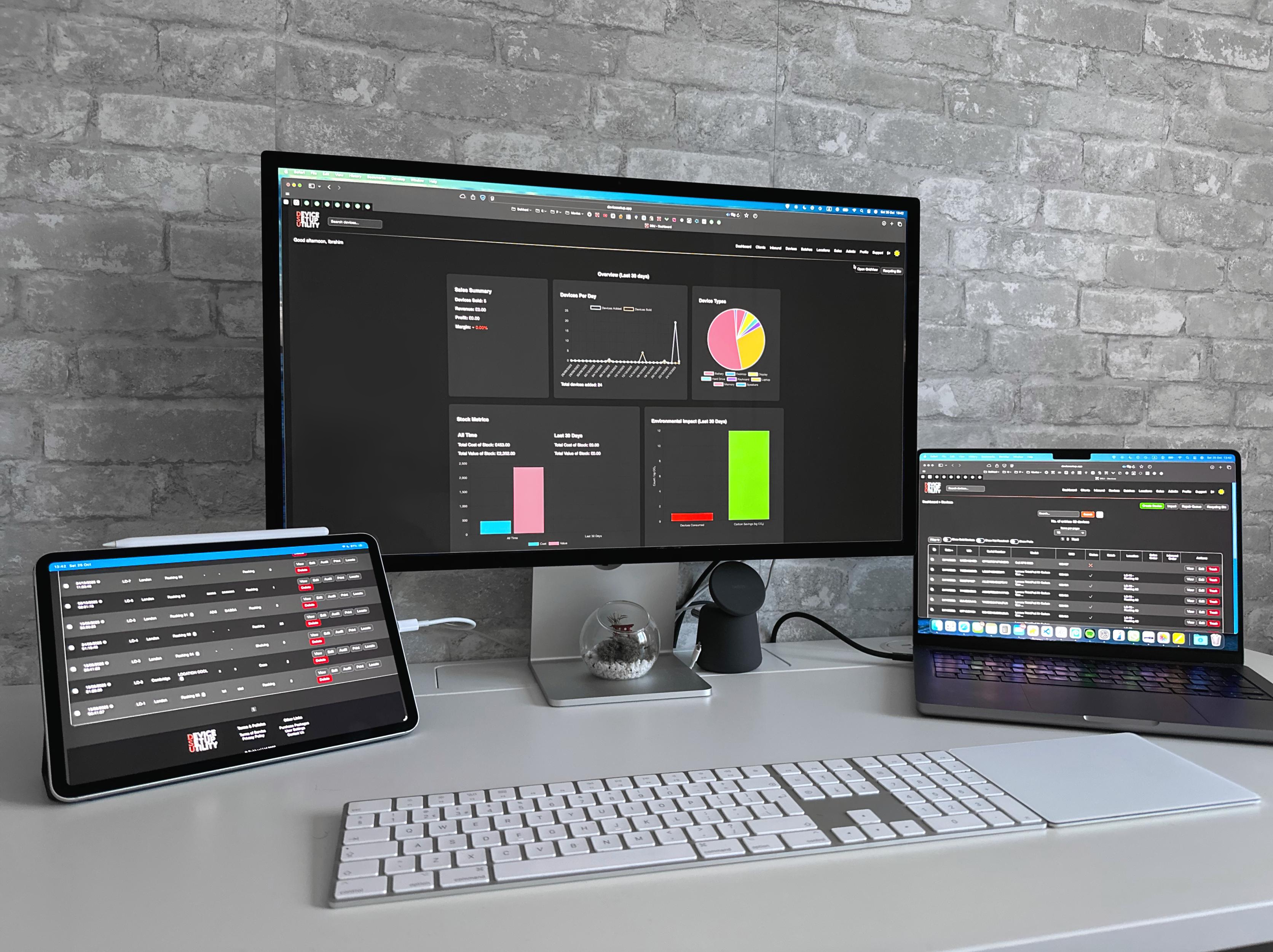 Desktop workspace showing DSU - Portal dashboard on multiple devices including a monitor, laptop, and tablet, displaying analytics charts and device management data.