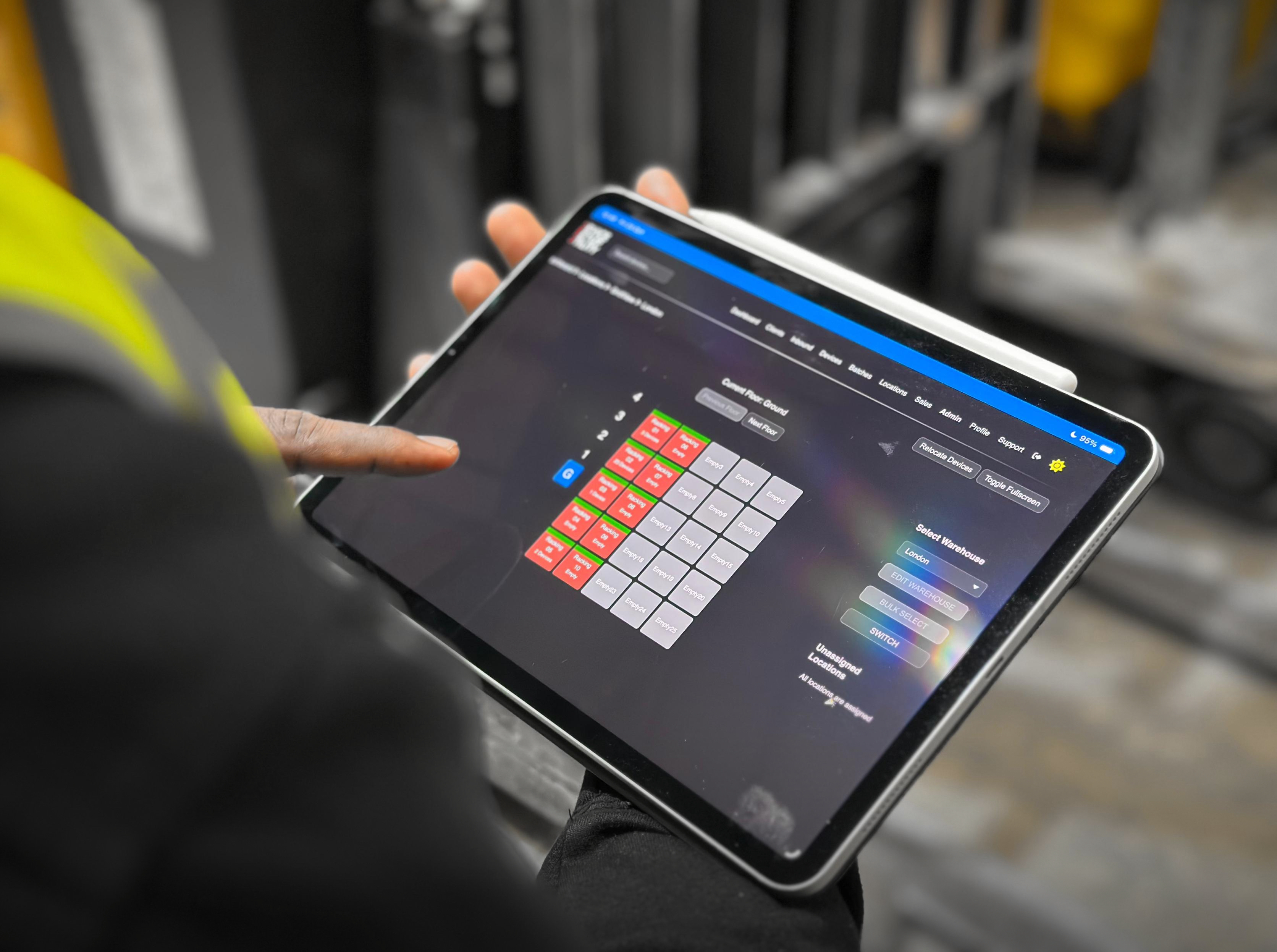 Person using the DSU - Portal GridView add-on on a tablet to manage warehouse device locations through an interactive grid interface.